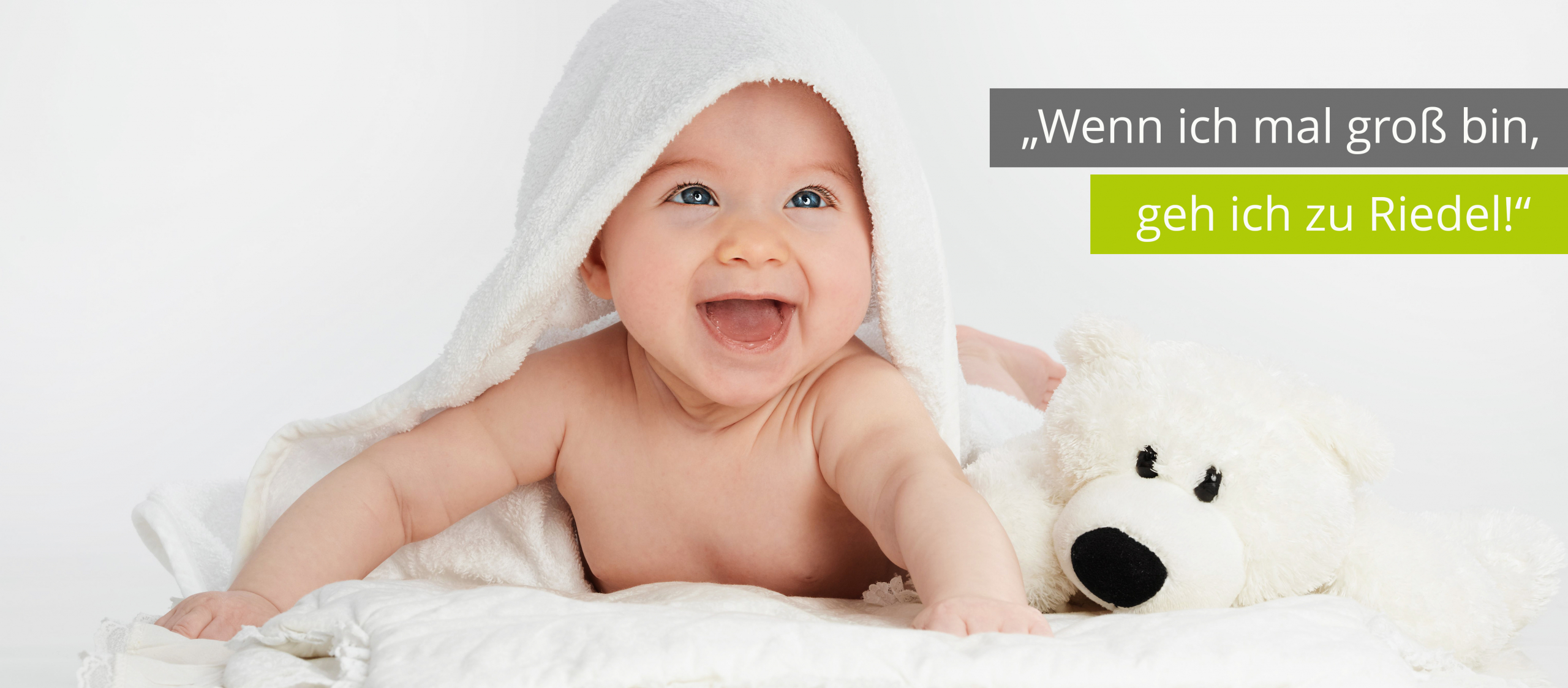 Titelbild Startseite - Wenn ich mal groß bin, geh ich zu Riedel, Sanitätshaus, Orthopädieschuhtechnik, Orthopädietechnik, Handwerk, Riedel Orthopädie, Gesundheit Das Bild zeigt ein Baby, welches lächeln auf einem Handtuch liegt und neben dem Baby liegt ein Kuscheltier. Darüber steht der Slogan: Wenn ich mal groß bin, geh ich zu Riedel.
